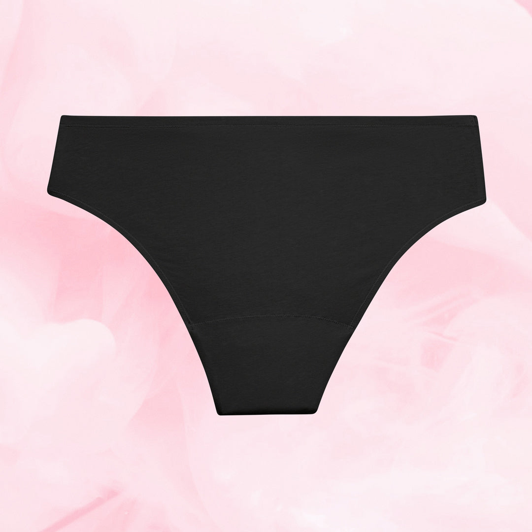 ComfortFit Essentials Brazilian menstruse, svart, flattliggende på rosa bakgrunn.