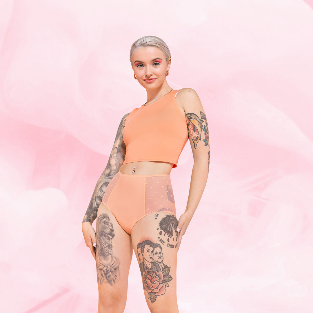 Person med High Waist Dots Lite Mens Menstruse mot rosa bakgrunn.