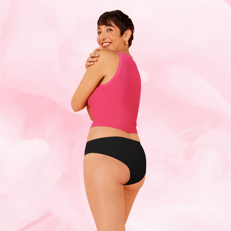 Kvinne i ComfortFit Essentials Brazilian menstruse, smilende over skulderen.